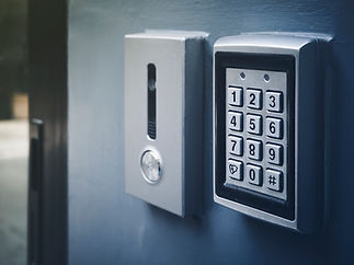 Close-up of a metallic keypad and intercom system mounted on a grey wall
