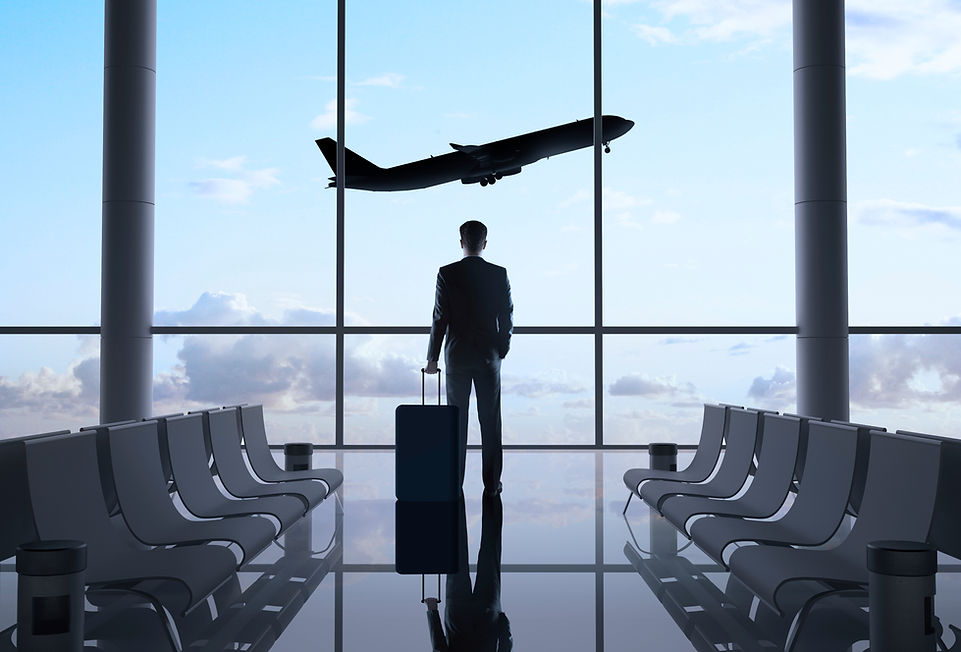Silhouette of traveler with luggage looking out at an airplane at the airport