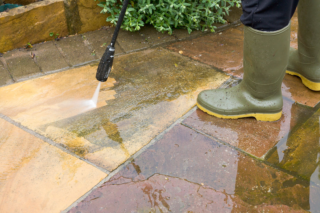 cropped shot of a person's legs while cleaning patio using high-pressure washer