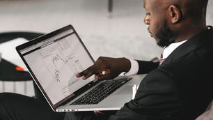 Investor analyzing stock charts and financial data on a computer, evaluating investment strategies for a covered call ETF.