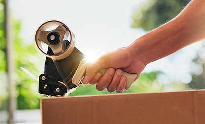 Closeup shot of an unrecognizable man closing a cardboard box with tape