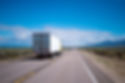 A lone truck drives down an empty desert highway
