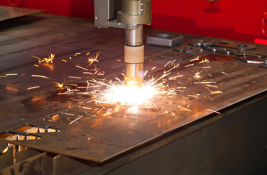 Industrial automated plasma profiling machine cutting through thick steel sheet with bright orange sparks flying