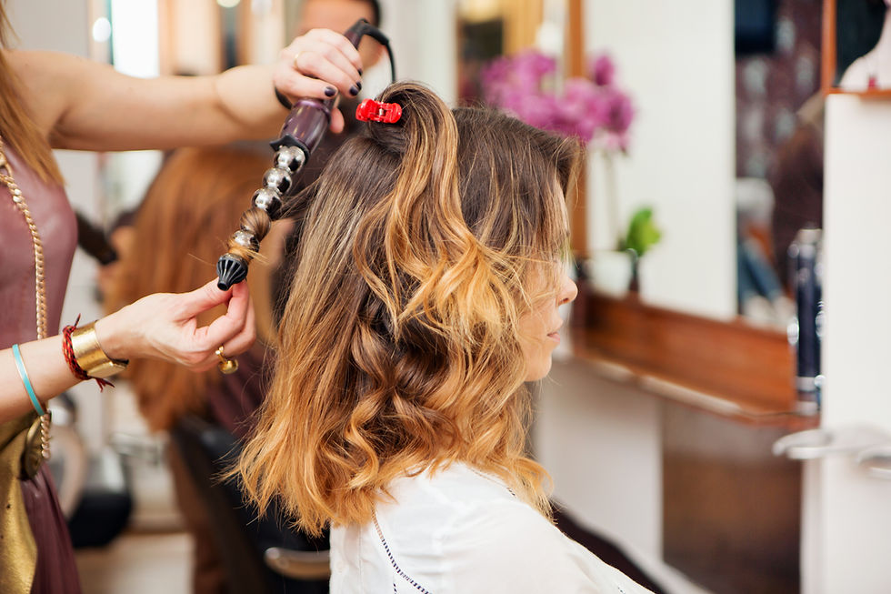 Hairstylist using a curling iron on a girl's brown hair in a salon