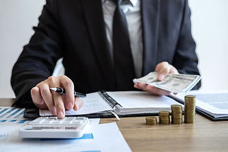A person in a suit calculates finances with a calculator
