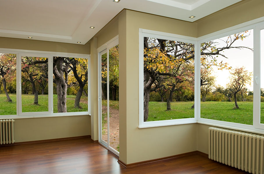 Interior of a room with large windows framing a view of an autumnal orchard