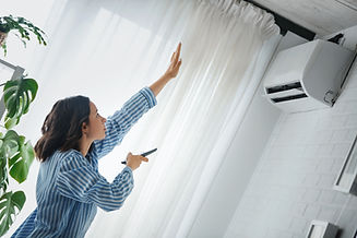 Woman holding a remote, checking if the air conditioner is cooling