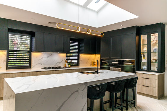 A modern kitchen with skylight, stone bench tops and 2 tone cabinets