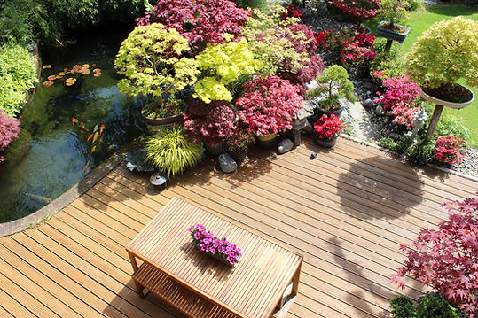 A beautifully landscaped garden featuring a pond with koi fish, surrounded by colorful flowering plants and trees