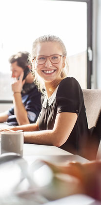 Lady smiles at a coworker as she works on her desktop.