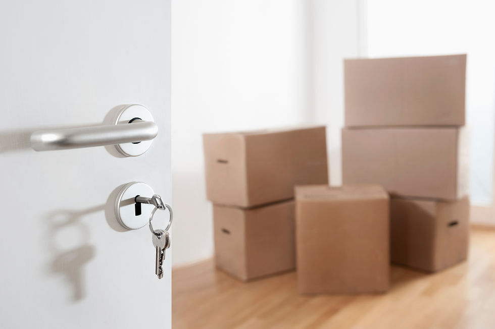 a set of keys in a white door lock with stacked moving boxes in the background