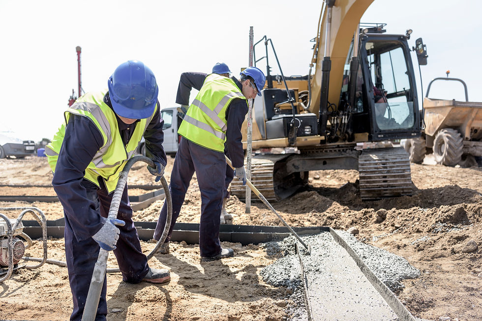 Construction workers pouring and smoothing concrete for a foundation at an outdoor building site