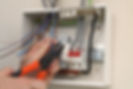An electrician connecting wire to fuse board