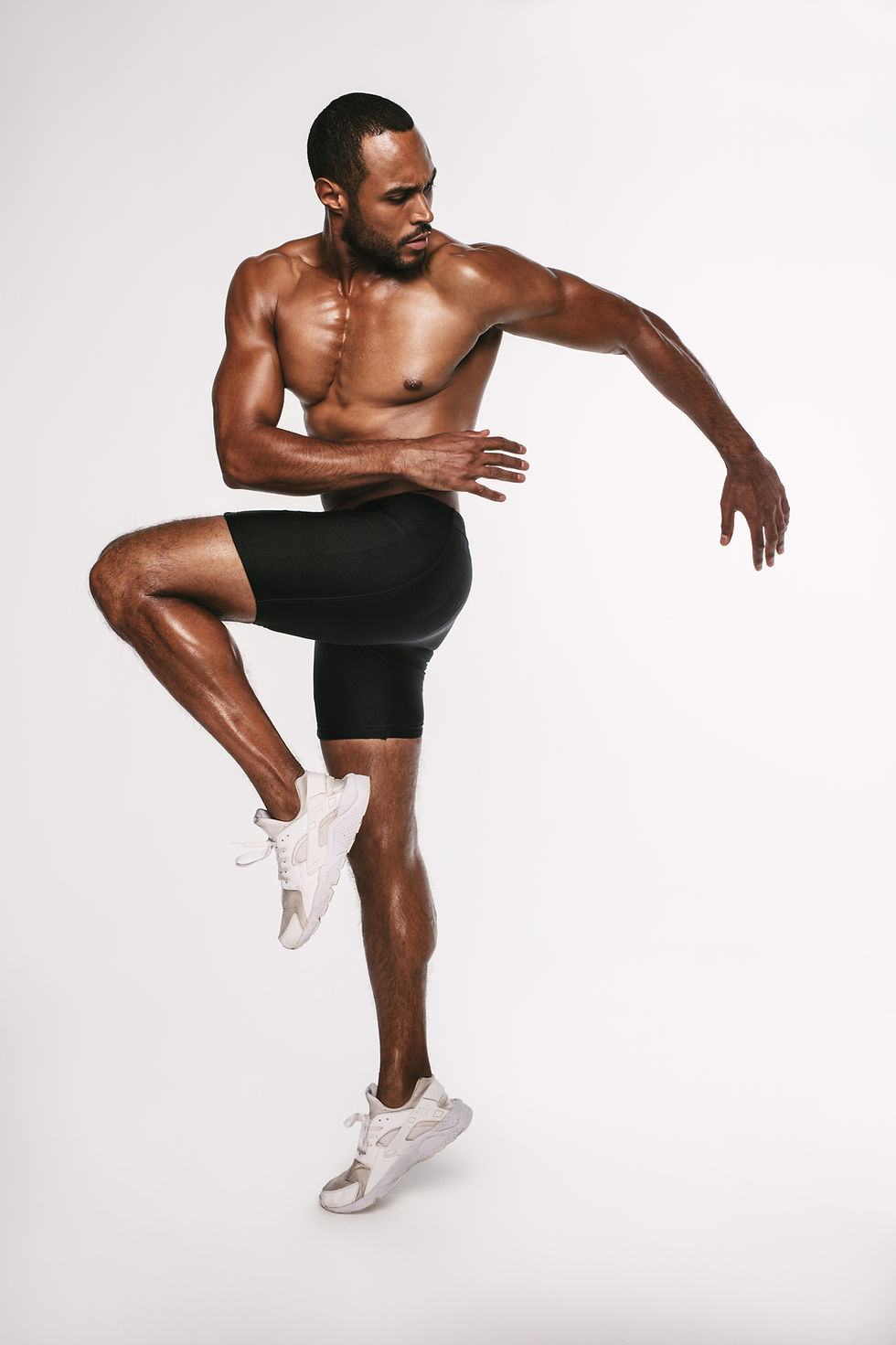 A man in motion wearing shorts and white sneakers.