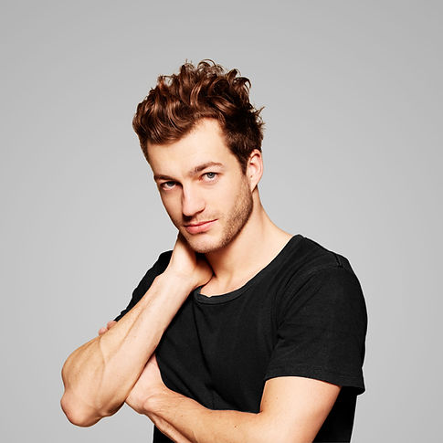 Young man with wavy hair posing with hand on neck