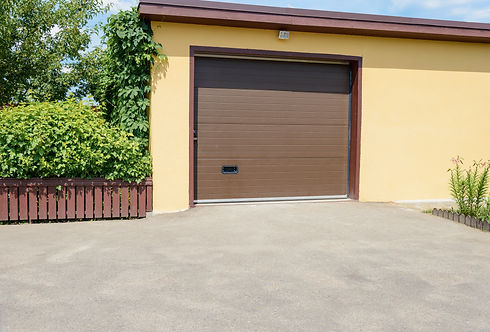 A brown garage door set in a yellow wall
