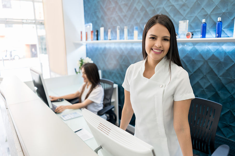 Beautiful business owner of a hair salon standing behind the reception smiling at camera v