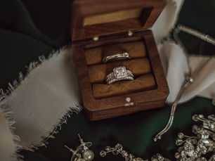 Bride and groom's wedding ring sets displayed together in a wooden ring box.