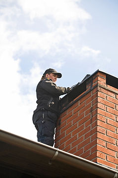 Female chimney sweeper on the roof cleaning a brich chimney