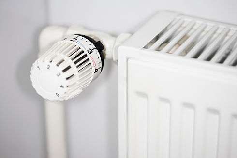Close-up of a white thermostatic radiator valve attached to a white panel radiator