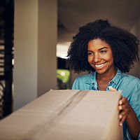 A person with curly hair holds a large cardboard box