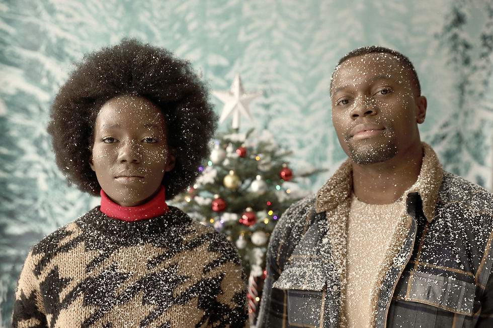 Stock image of a Black couple in snow, with a Christmas tree in the background.