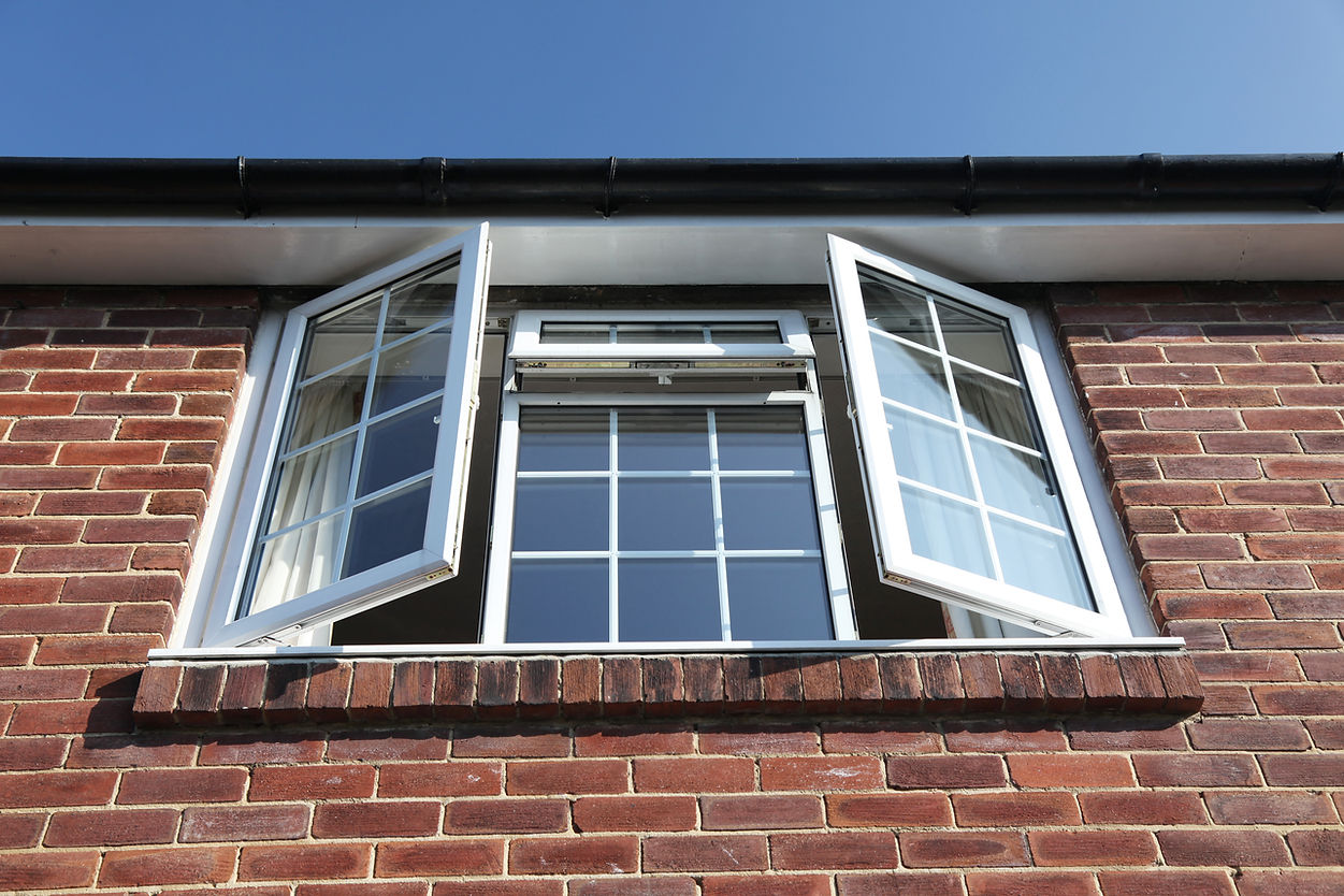 Open casement windows on a brick building, framed by a clear blue sky
