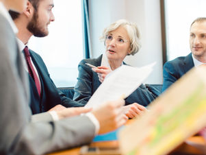 אנשי עסקים יושבים סביב שולחן, עוסקים בדיון עסקי חשוב.