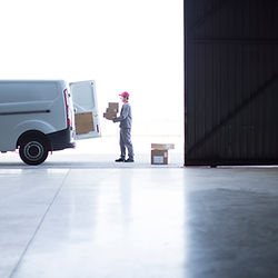Courier worker loading van with boxes at a warehouse