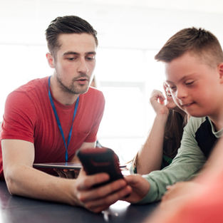 Special needs child receives assistance from special education teacher in a classroom.