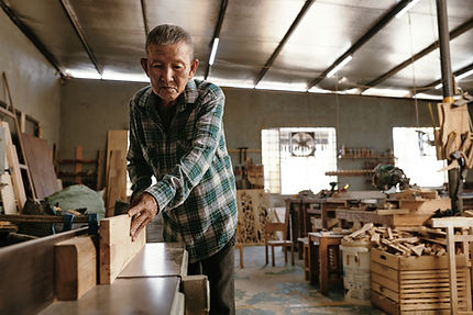 Old Asian carpenter cutting wood
