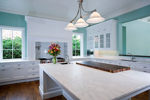 A kitchen featuring a marble island and white cabinetry