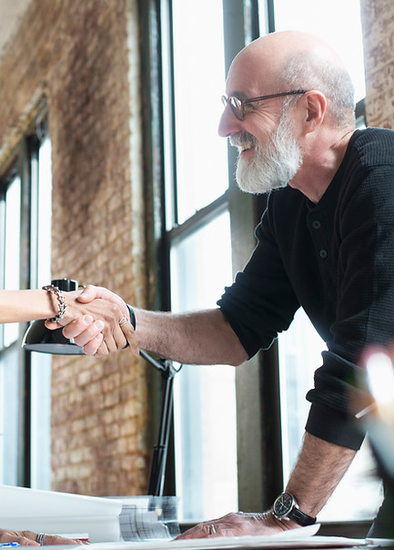 Two professionals shaking hands across a desk in a bright office
