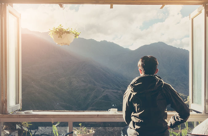 Man looking outside of the window with a mountain view