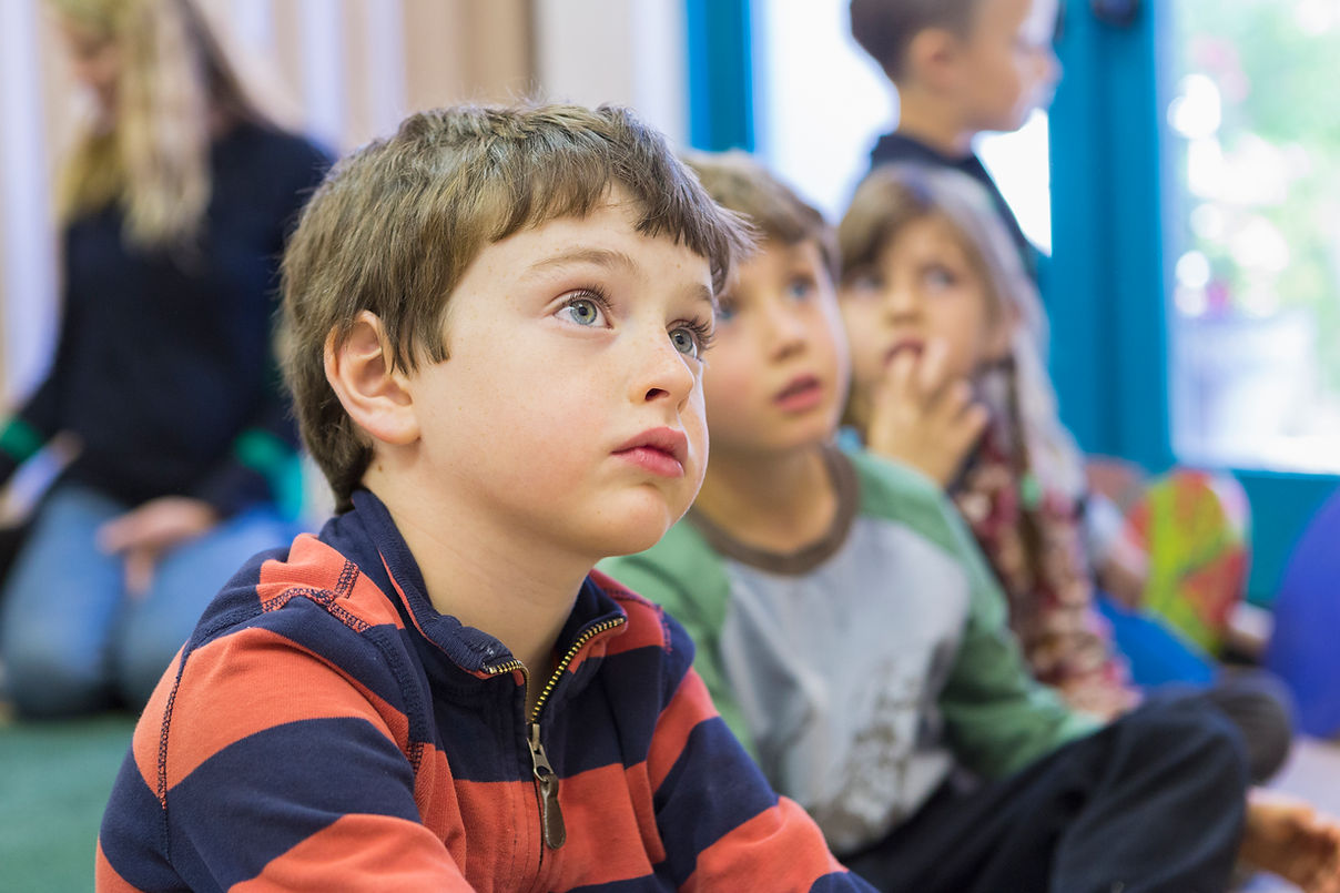 Children sit attentively in a room