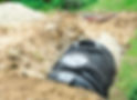 A large black ribbed septic tank being installed in an excavated trench surrounded by soil