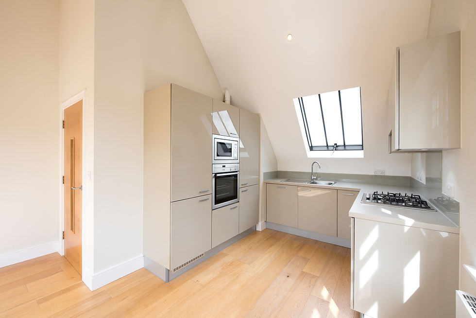 Unfurnished modern loft kitchen with glossy grey cabinets, skylight window, and hardwood floors