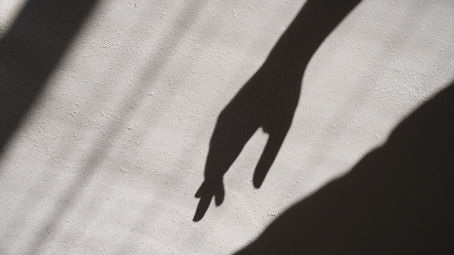 Person standing near a closed door with light shining through, symbolizing protective patterns, inner confinement, and the beginning of spiritual freedom.
