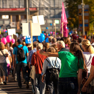 Crowd walking through a city street holding signs, symbolizing uncertainty and modern stress that can contribute to existential anxiety.
