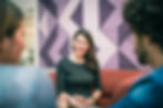 A woman taking notes while engaged in conversation with a couple