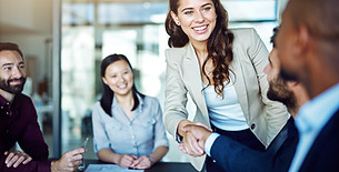 Diverse group of smiling colleagues shaking hands across an office table during a meeting