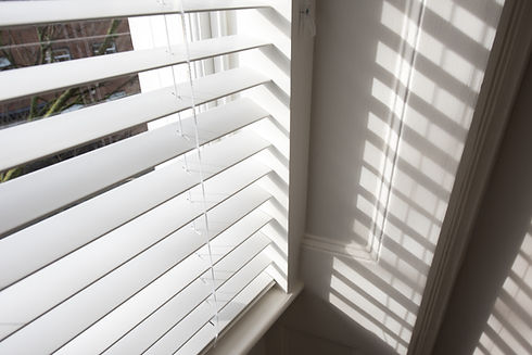 Sunlight streaming through white blinds