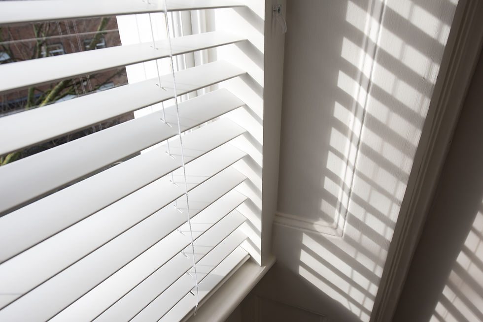 White horizontal window blinds casting striped shadows on a wall