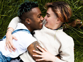 Couple lying in the grass while lovingly looking into each others.