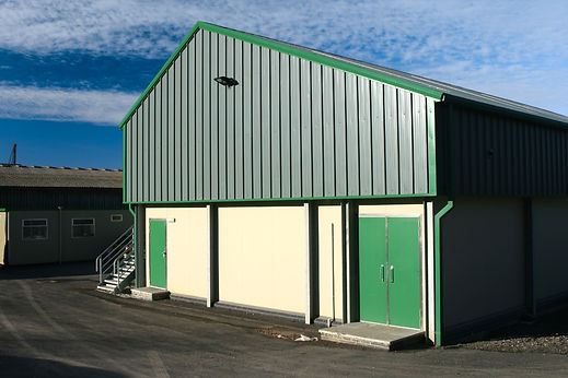 External view of a large commercial industrial unit with newly spray painted green cladding and doors
