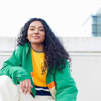 Garota de cabelo cacheado vestindo roupas coloridas e mostrando seu estilo próprio.
