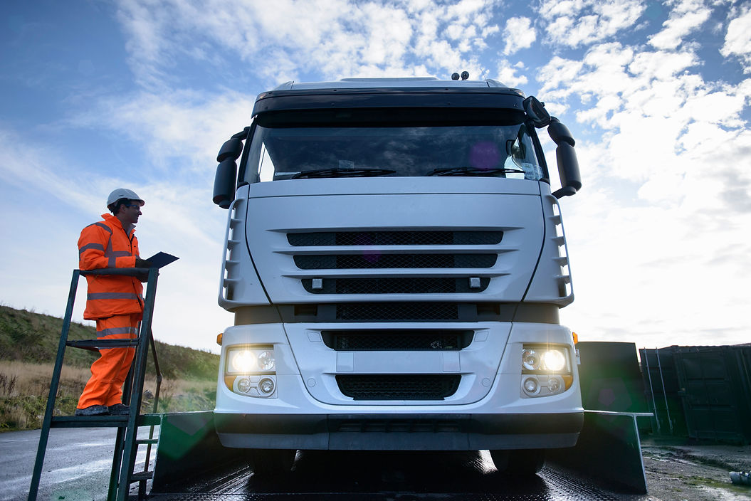 a worker with clipboard and front view of a truck