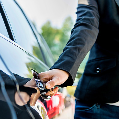 Chauffeur opening door of a black car