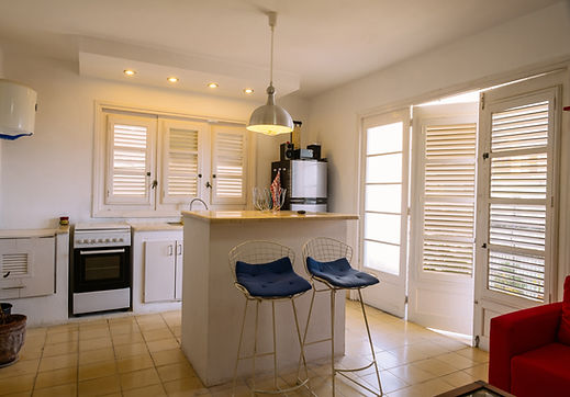 Modern kitchen interior with cafe-style window shutters and breakfast bar seating