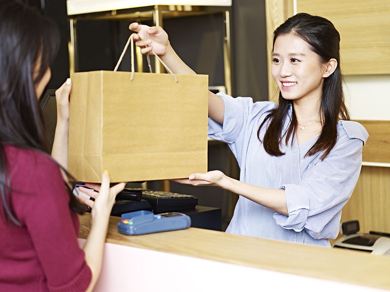 Person Handing Over Shopping Bag